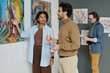 © pressmaster - Young people discussing pictures on the wall while enjoying modern art in art gallery