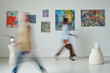 © pressmaster - Blurred motion of people passing through the paintings on the wall in art gallery