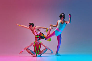 Flexible, stylish men in vintage sportswear training, stretching against gradient blue pink studio background in neon light. Concept of sportive and active lifestyle, humor, retro style. Ad