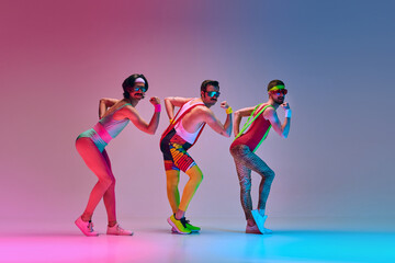Athletic, funny men in colorful vintage sportver training against gradient blue pink studio background in neon light. Concept of sportive and active lifestyle, humor, retro style. Ad