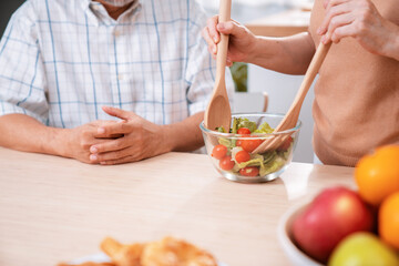 Wall Mural - Contented senior couples who are happy to cook together with bread veggies and fruit in their kitchen.