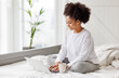 © JenkoAtaman - happy young african american woman relaxing with laptop at home lying in bed  .