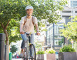 © KOTO - Portrait smiling young woman in helmet riding bicycle in urban park