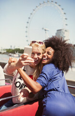 Wall Mural - Enthusiastic friends taking selfie on double-decker bus London Eye 