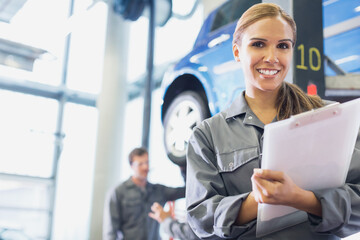 Wall Mural - Portrait smiling mechanic with clipboard in auto repair shop