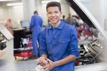 Portrait smiling mechanic leaning on car in auto repair shop