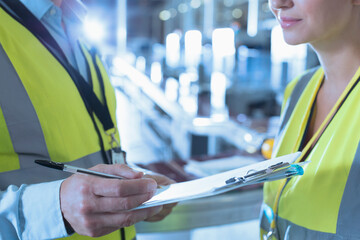 Wall Mural - Close up worker and supervisor with clipboard in factory