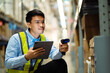 © KANGWANS - Male warehouse worker with barcode scanner in a large warehouse. Workers in a warehouse scan parcels for retail delivery and transportation.