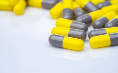 Wall Mural - Closeup yellow and gray capsule pills on white background. Prescription drugs. Pharmaceutical industry. Health and medical care concept. Pharmacy products. Capsule pills production manufacturing.