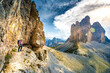 © Michael - Young athletic woman enjoys scenic view on Tre Cime from via ferrata in the evening. Tre Cime, Dolomites, South Tirol, Italy, Europe.