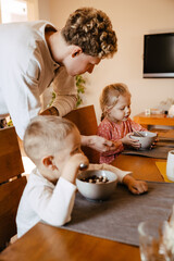 Wall Mural - Father watching his kids eating breakfast in kitchen