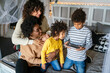 © NDABCREATIVITY - Happy multiethnic family having fun with digital device at home. Family gadget technology concept.