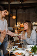 © Drobot Dean - Young woman blowing candles on cake while celebrating birthday among friends in restaurant