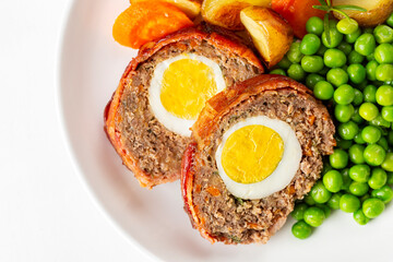 Wall Mural - Close-up of slices of baked meatloaf stuffed with hard-boiled eggs, yolks,  cooked vegetables.