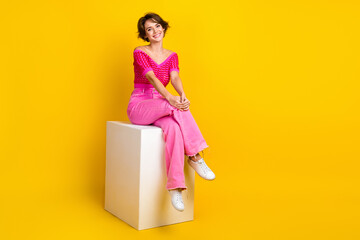 Sticker - Full length body photo of sit podium comfortable beautiful lady wear pink stylish outfit chilling advertisement isolated on yellow color background