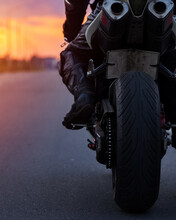 Close-up Of The Rear Wheel Of A Sportbike Motorcycle, Dual Exhaust. Biker On A Motorcycle At Sunset