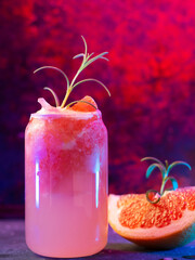 Wall Mural - glass of grapefruit tonic. freshly squeezed grapefruit juice, rosemary sprig. neon colored light