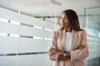 © insta_photos - Confident smiling young professional business woman ceo corporate leader, female African American lawyer or manager executive wearing suit standing arms crossed in office, looking away, thinking.