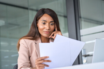 Busy young African American business woman account manager executive expert checking tax papers, analyzing corporate bills thinking on risks reading corporate financial report working in office.