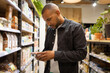 © ADDICTIVE STOCK - Concentrated black man using smartphone in grocery store