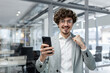 © Liubomir - Portrait of successful businessman investor, mature boss in suit and glasses looking at camera and happy celebrating victory success, man holding smartphone received online news of good achievement.