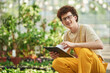 © standret - Quality control, with notepad. Young man with curly hair and in glasses is in greenhouse