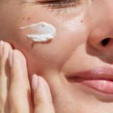 Hydration. Cream smear. Beauty close up portrait of young woman with a healthy glowing skin is applying a skincare product.