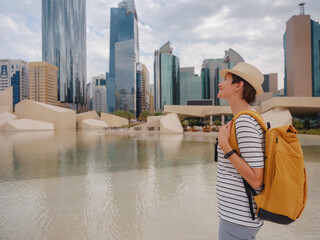 Wall Mural - travel to the United Arab Emirates, Happy young asian female traveler with backpack and hat in big city of Abu Dhabi. Qasr al-Hosn first structure of the city