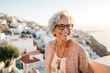 © Leon Waltz - Portrait of a smiling senior woman wearing eyeglasses and looking at camera while standing in front of the sea