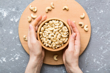 Canvas Print - Woman hands holding a wooden bowl with cashew nuts. Healthy food and snack. Vegetarian snacks of different nuts