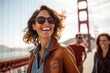 © Anne Schaum - Lifestyle portrait photography of a grinning woman in her 40s that is smiling with friends at the Golden Gate Bridge in San Francisco USA . Generative AI