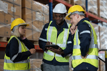 Male and female warehouse workers working checks stock and inventory and standing talking together at storage warehouse. Group of warehouse workers discuss and training work in distribution branch