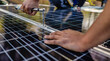 © PintoArt - A worker's hand screws solar panels onto a roof with a torque wrench in beautiful sunlight