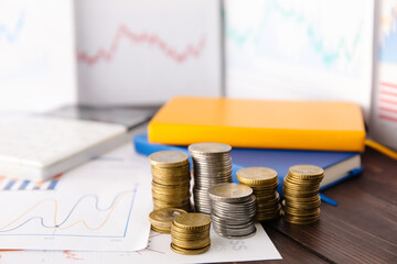 Canvas Print - Stacks of coins and diagrams on table, closeup. Exchange rate concept