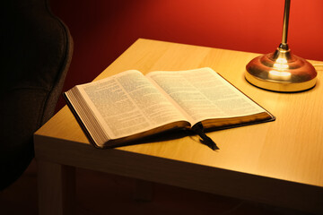 Wall Mural - Open Holy Bible on table near red wall