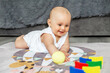 © Olha Tsiplyar - Smiling baby creep on floor of nursery grabbing colorful ball. Baby development. Sensory experience