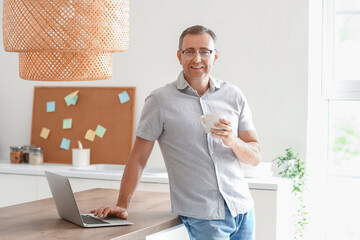 Poster - Mature man with eyeglasses and cup of coffee in kitchen