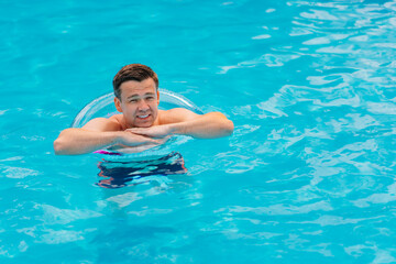 Wall Mural - Portrait of a cheerful middle-aged man in the pool with inflatable lifebuoy.