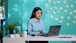© DC Studio - Secretary wearing headphones following directives received from manager during online videocall. Asian employee in video conference meeting with her boss in colorful office over blue studio background