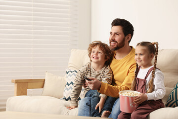 Sticker - Happy father and children watching TV with popcorn on sofa indoors, space for text