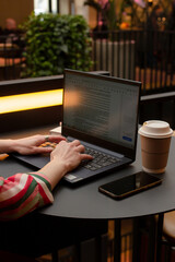 female hands on keyboard, woman working on a laptop at the table in cafe