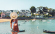Woman tourist with white hat looking at view of typical fishing village in Britttany- France ( Sainte Marine, Combrit)