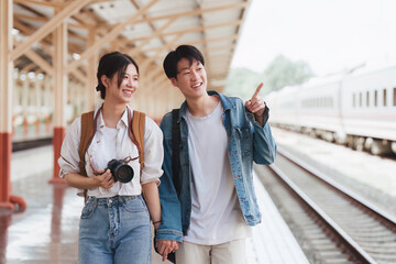 Asian couple at railway station have happy moment. Tourism and travel in the summer