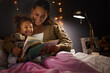 © Micah C/peopleimages.com - Night, book and mother with daughter in bedroom for storytelling, fantasy and creative. Education, learning and love with woman reading to young girl in family home for bedtime, literature and relax