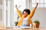 Fototapeta Panele - Joyful   business woman freelancer  entrepreneur smiling and rejoices in victory while sitting at desk   and working at laptop   after finishing project  in home office
