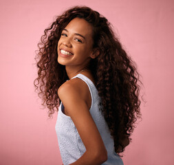 Wall Mural - Hair care, portrait and woman in a studio with a natural, long and curly beauty salon hairstyle. Happy, smile and brunette female model with a keratin cosmetic treatment isolated by pink background.