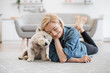 canvas print picture - Kind female person and faithful small terrier snuggling to each other with heads while staying on wooden floor at home. Affectionate woman and cuddly Westie enjoying bonding interaction on sunny day.