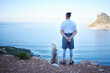 Mountain, lake and back of man with dog for hiking, walking and fresh air together outdoors. Traveling, friendship and male person with pet husky relax for freedom, adventure and exercise in nature