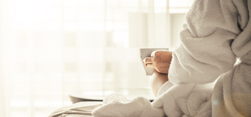 Wall Mural - Woman in white bathrobe and towel lying on sofa and relaxing with tea at the roof.