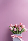 Fototapeta Tulipany - A vase filled with pink tulips on a table. Generative AI. Copy space, place for text.